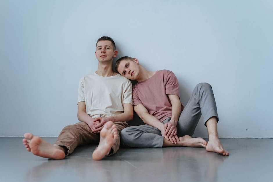 Two young men sitting together inside, sharing a tender and loving moment.