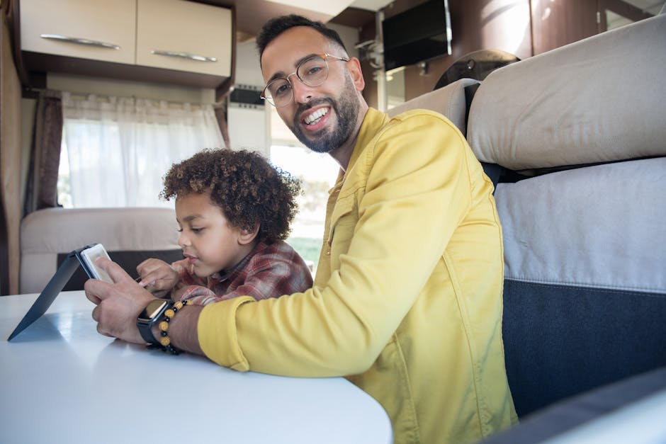 A joyful father and son using a tablet together indoors, showcasing family bonding.